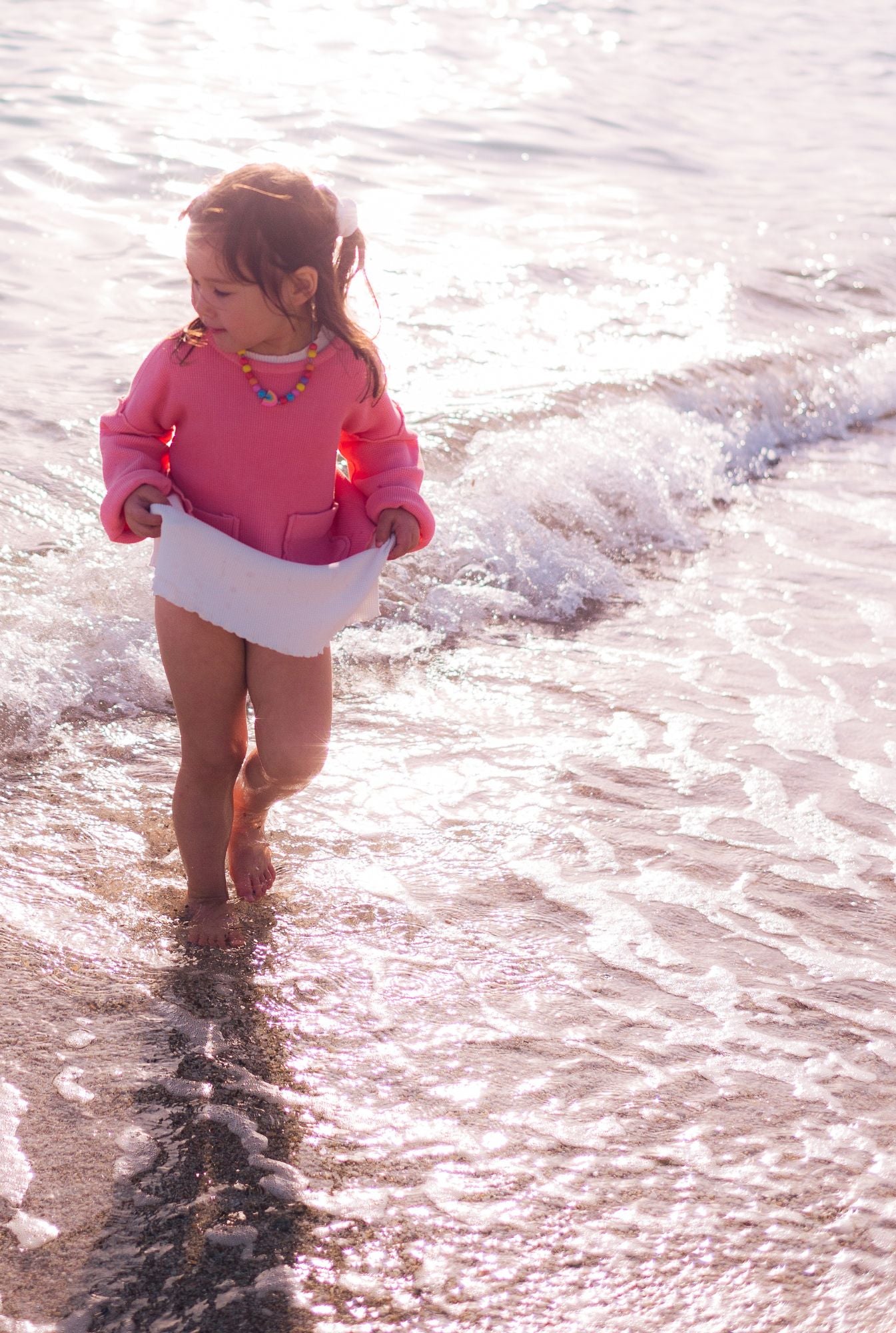 A little girl in her organic cotton pink top and white dress.