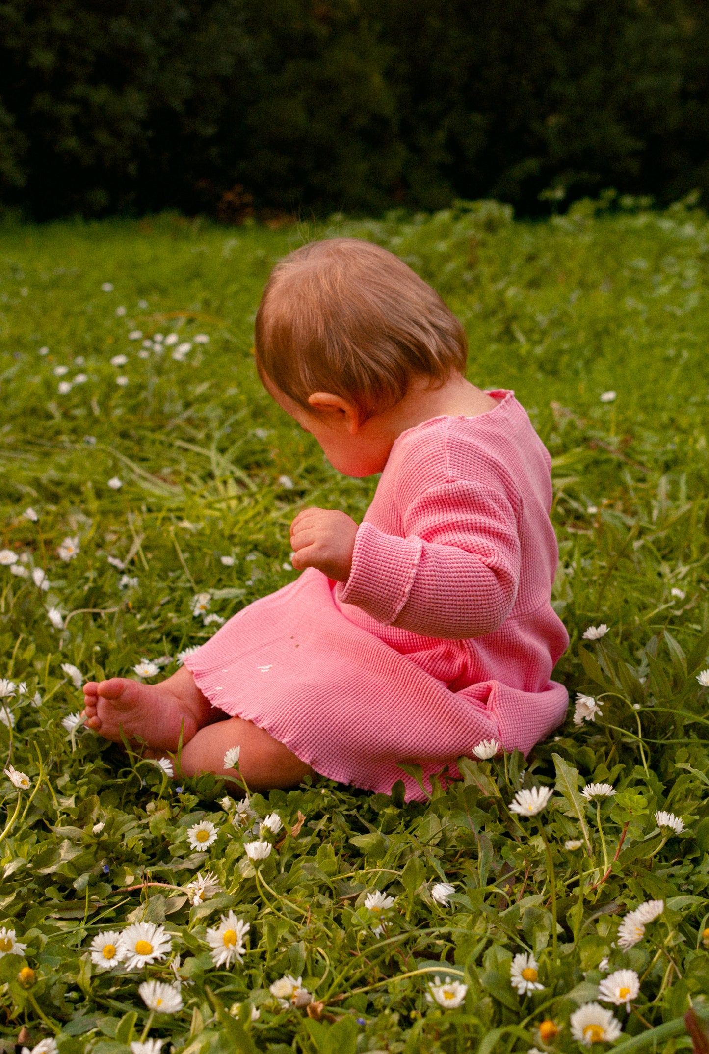 A little girl playing in the field. She is wearing a comfortable, breathable 100% organic cotton waffle dress designed for everyday play.