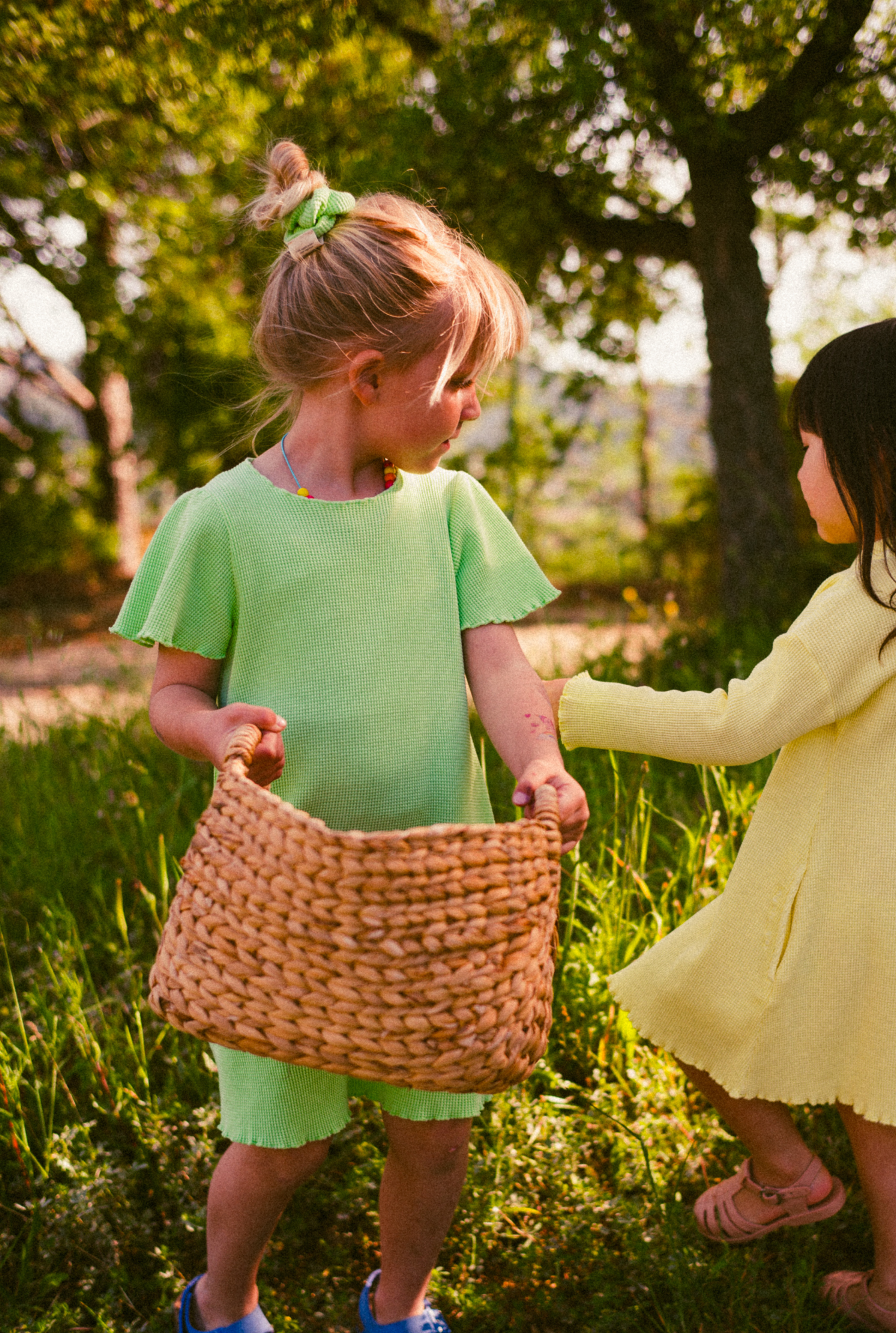 Summer days in South France. Two little girls picking flowers in their colorful and comfortable 100% organic cotton waffle dresses.