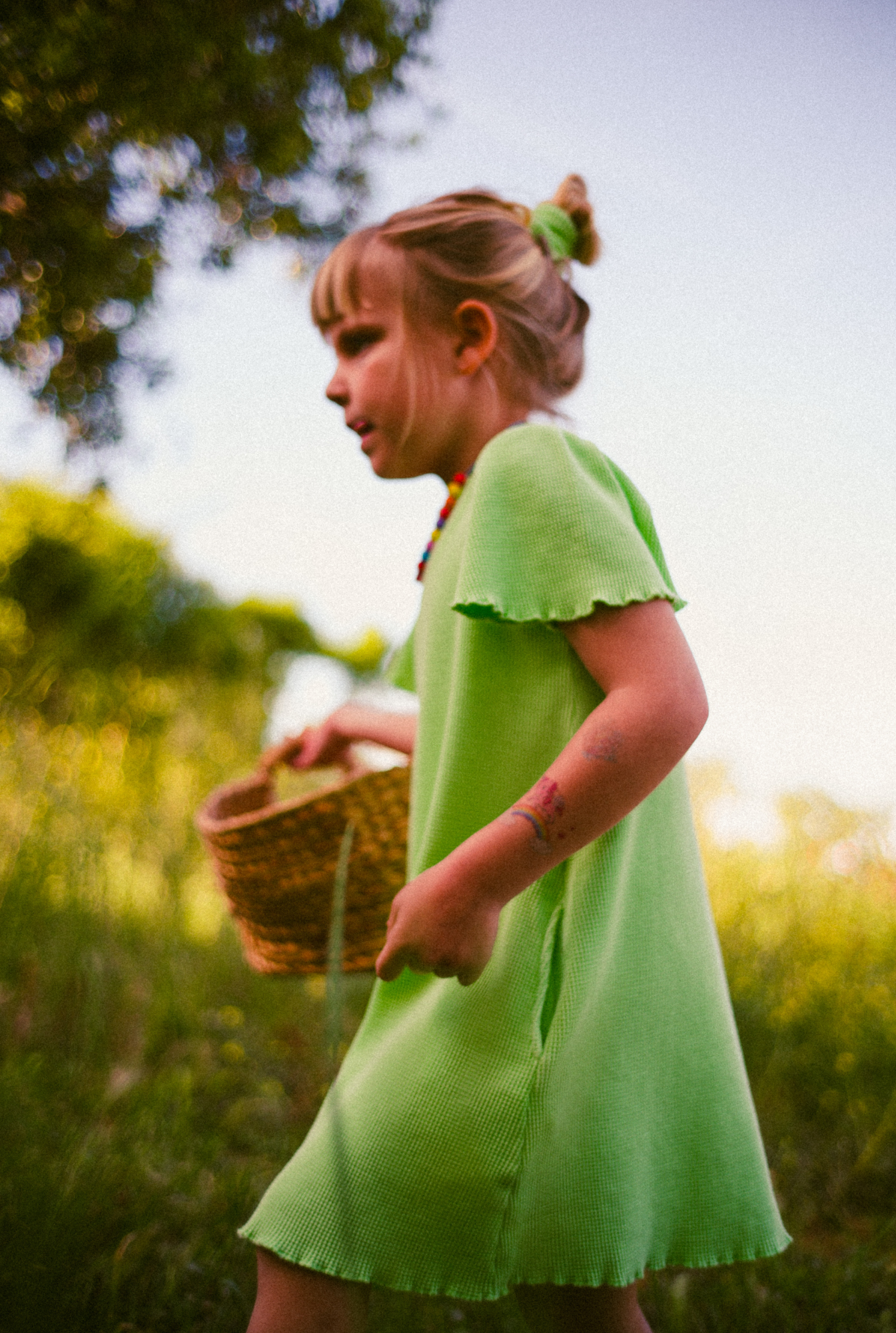 A little girl playing in the field in South of France. She is wearing a beautiful light green dress made from 100% organic cotton. The dress is soft, comfortable and comes with side pockets.