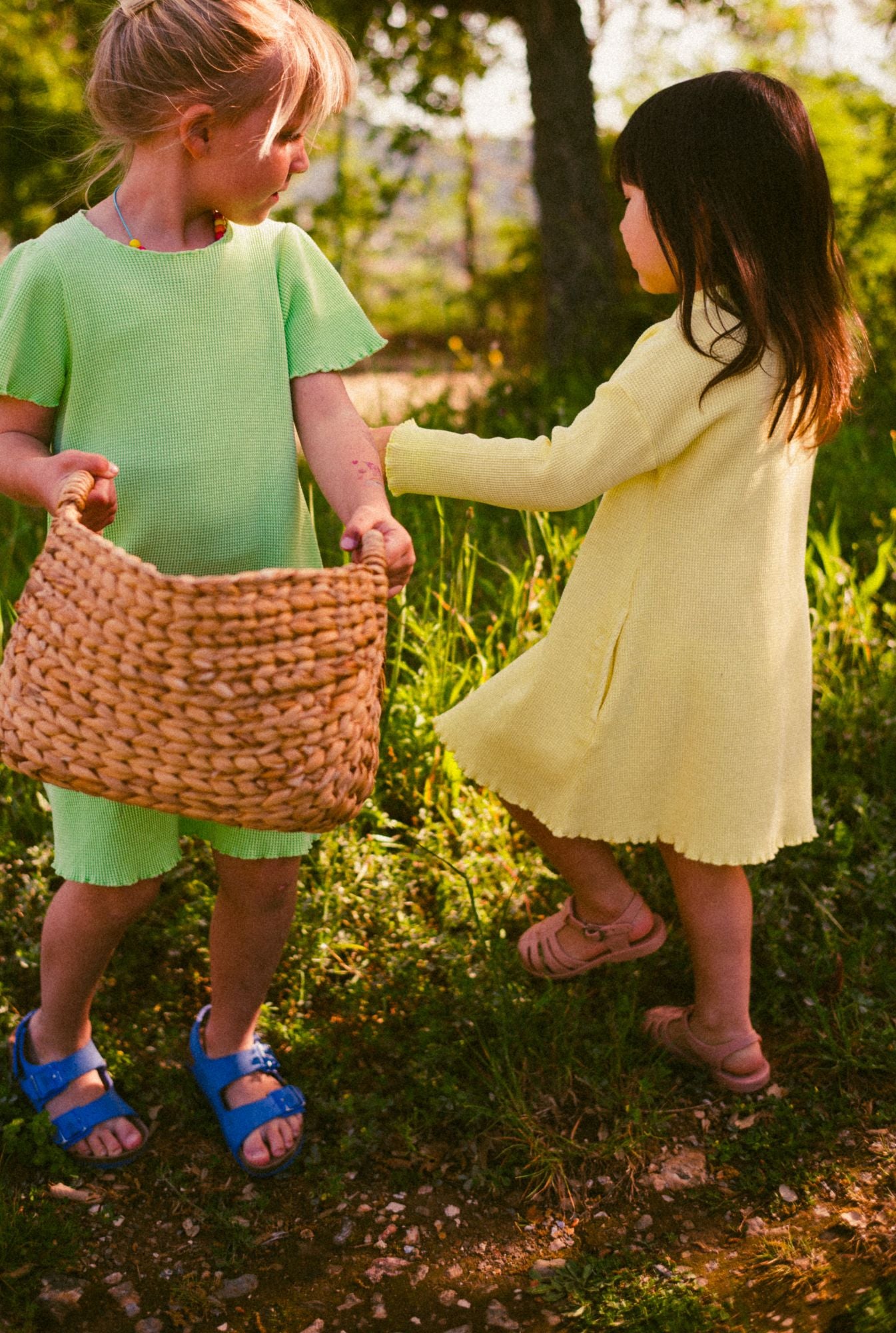little girls playing in the field and wearing comfortable dresses in green and yellow. Made with 100% organic cotton and garment dyed with natural minerals. Both dresses have pockets.