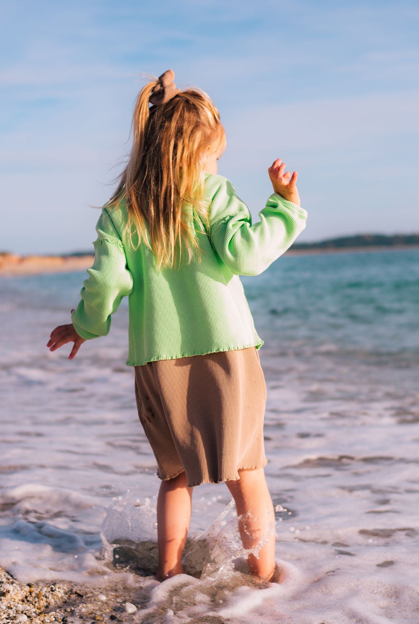 Little girl wearing a light green top and short sleeve dress made from organic cotton and garment-dyed with natural minerals.