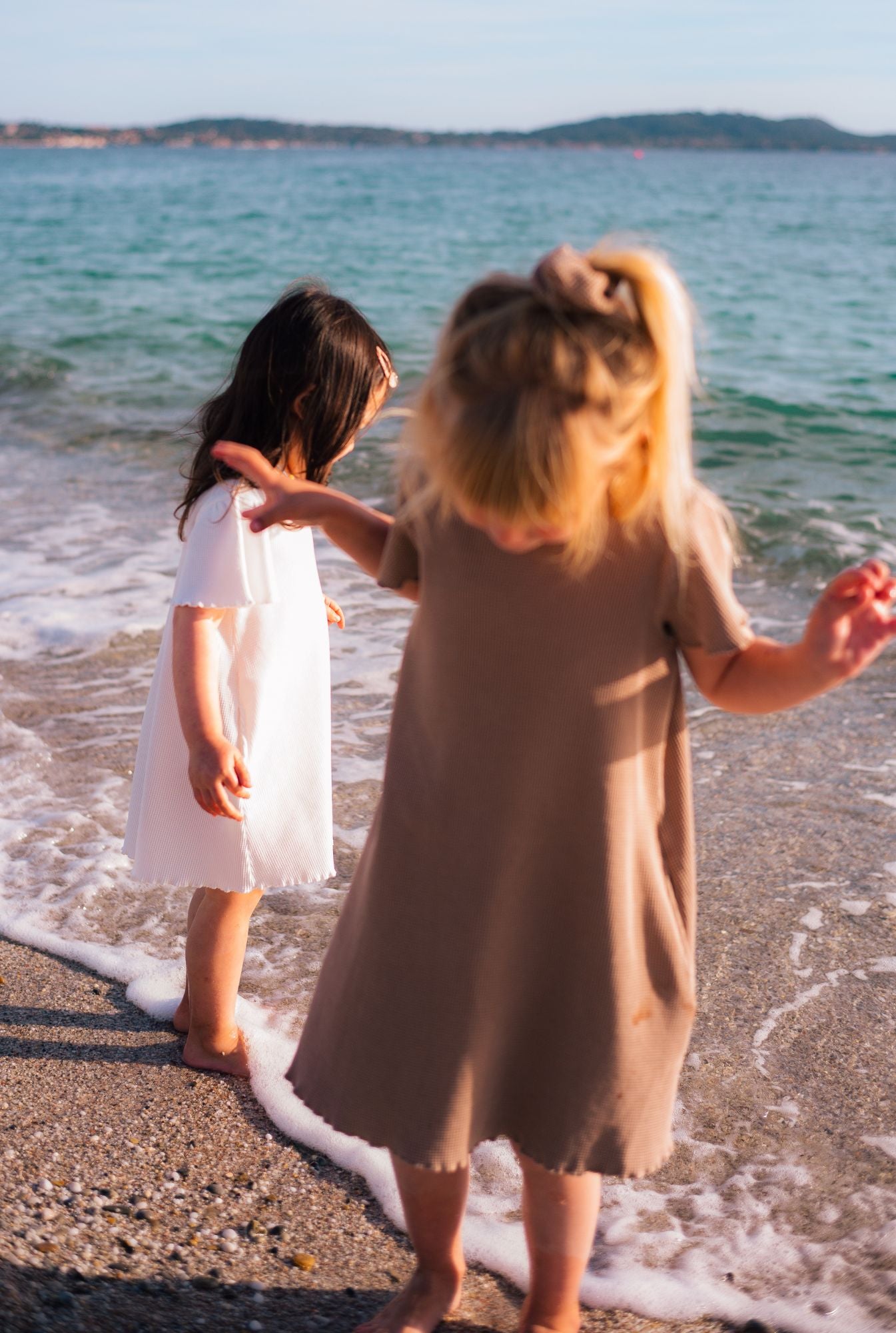 Two girls by the beach in South of France wearing beautiful organic cotton waffle dresses. Made by Tiny Advocates, these dresses are 100% organic cotton and garment dyed in natural minerals.