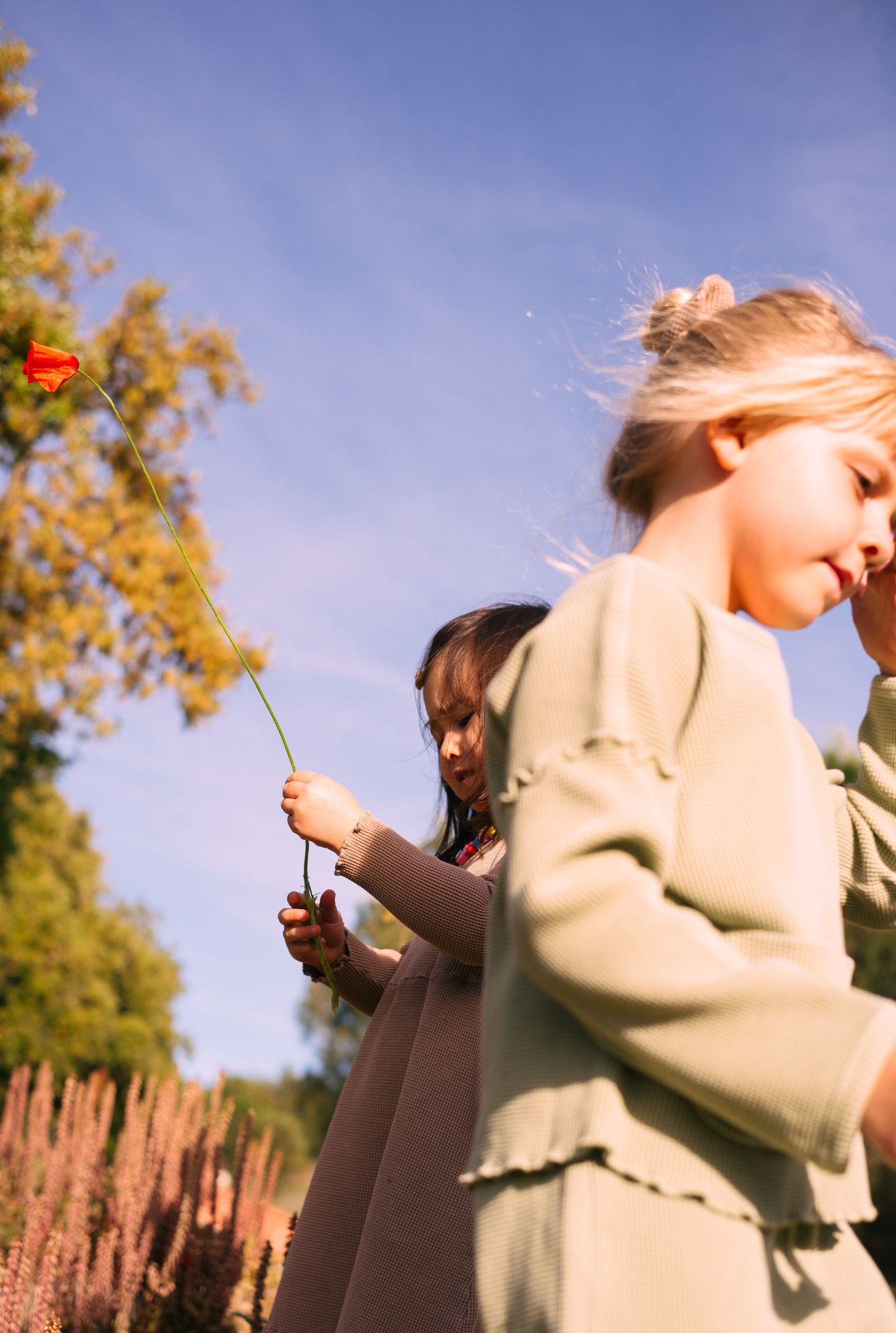 Kids in nature. Two little girls playing in the field and wearing comfortable, stylish tops and pants. All clothes are made from 100% organic cotton and garment-dyed with natural minerals.