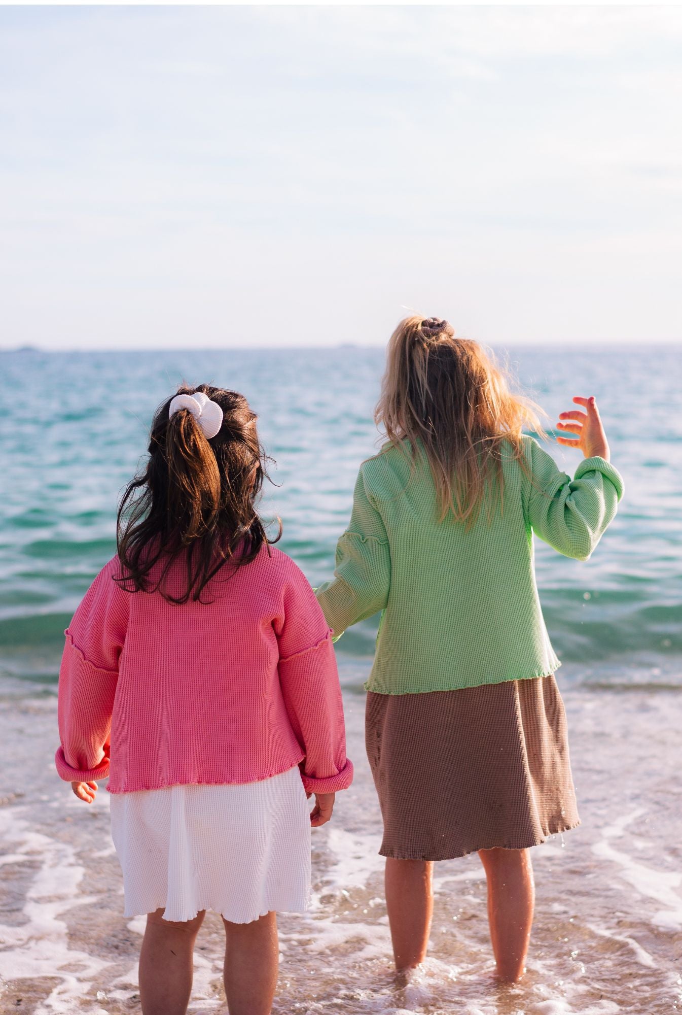 Playful kids by the beach wearing organic cotton clothes. Made for play, travel and school.