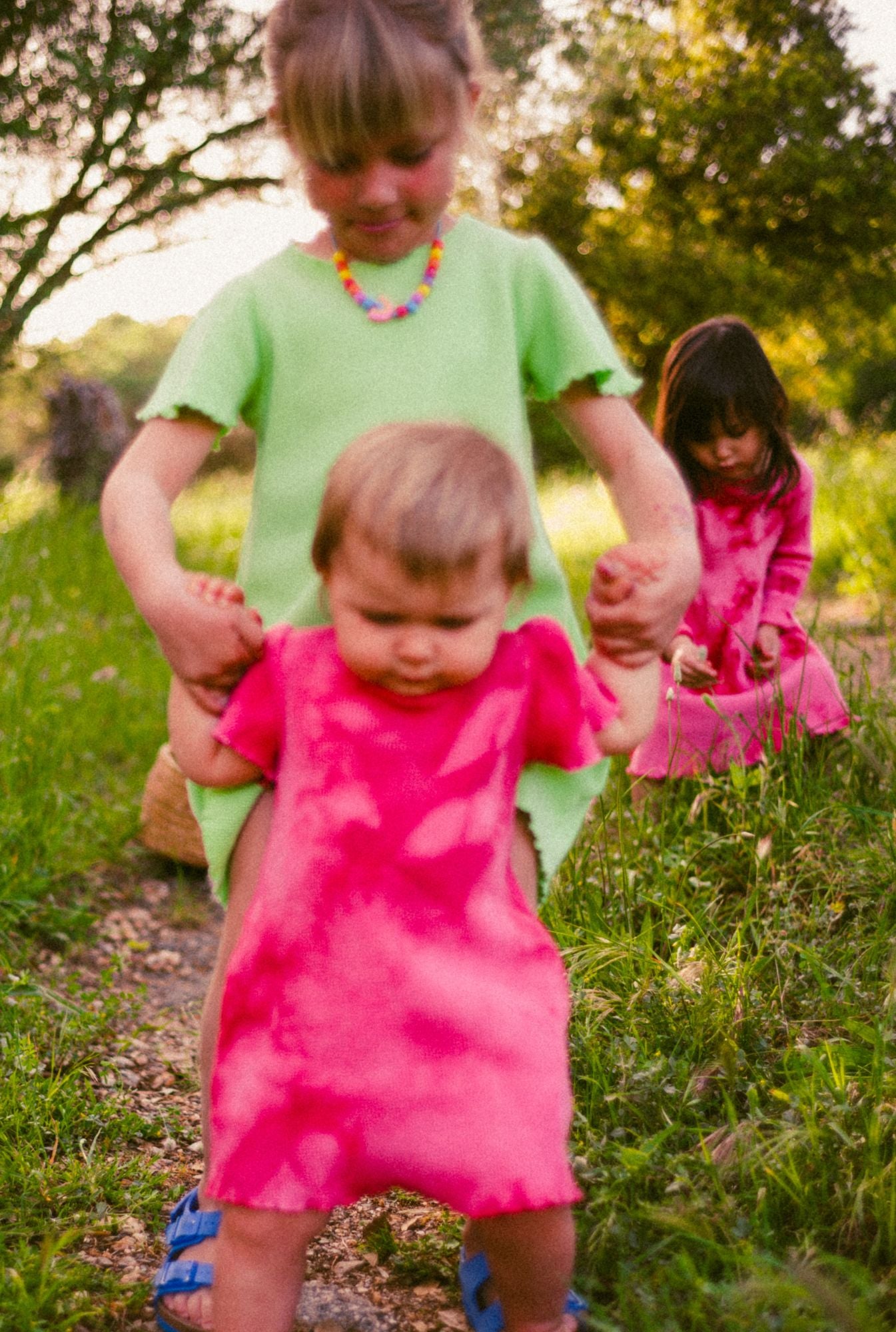 Little girls playing in the field, picking flowers. They all wear dresses by @tiny_advocates, made from 100% organic cotton waffle and garment dyed in natural mineral pigments.