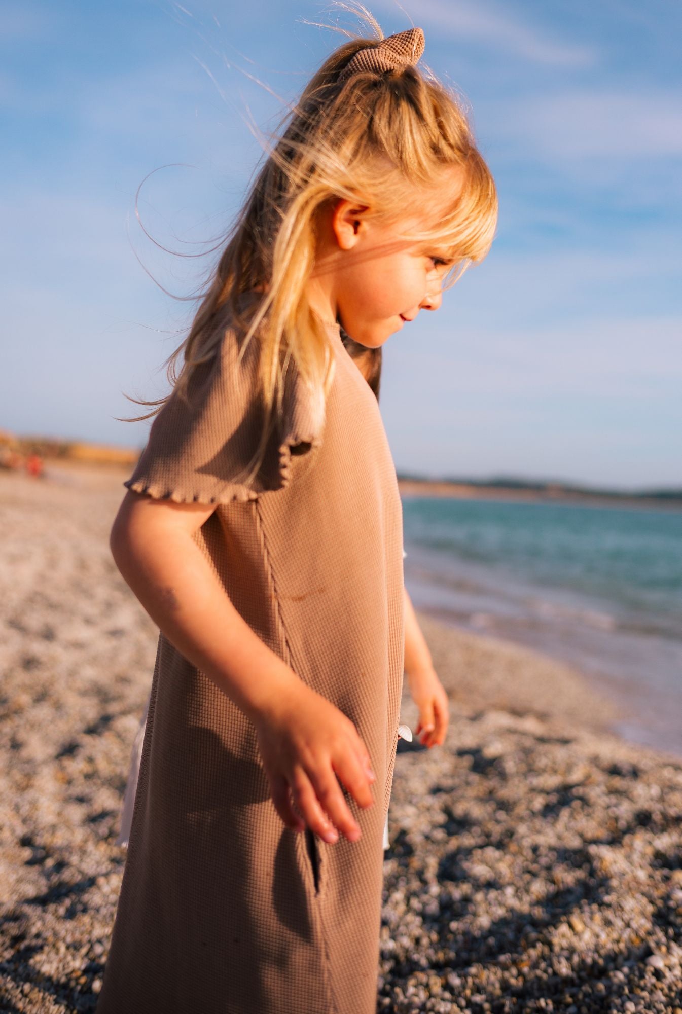 A little girl standing on the beach. She is wearing a comfortable and stylish short sleeve dress made from organic cotton and garment dyed in natural minerals.