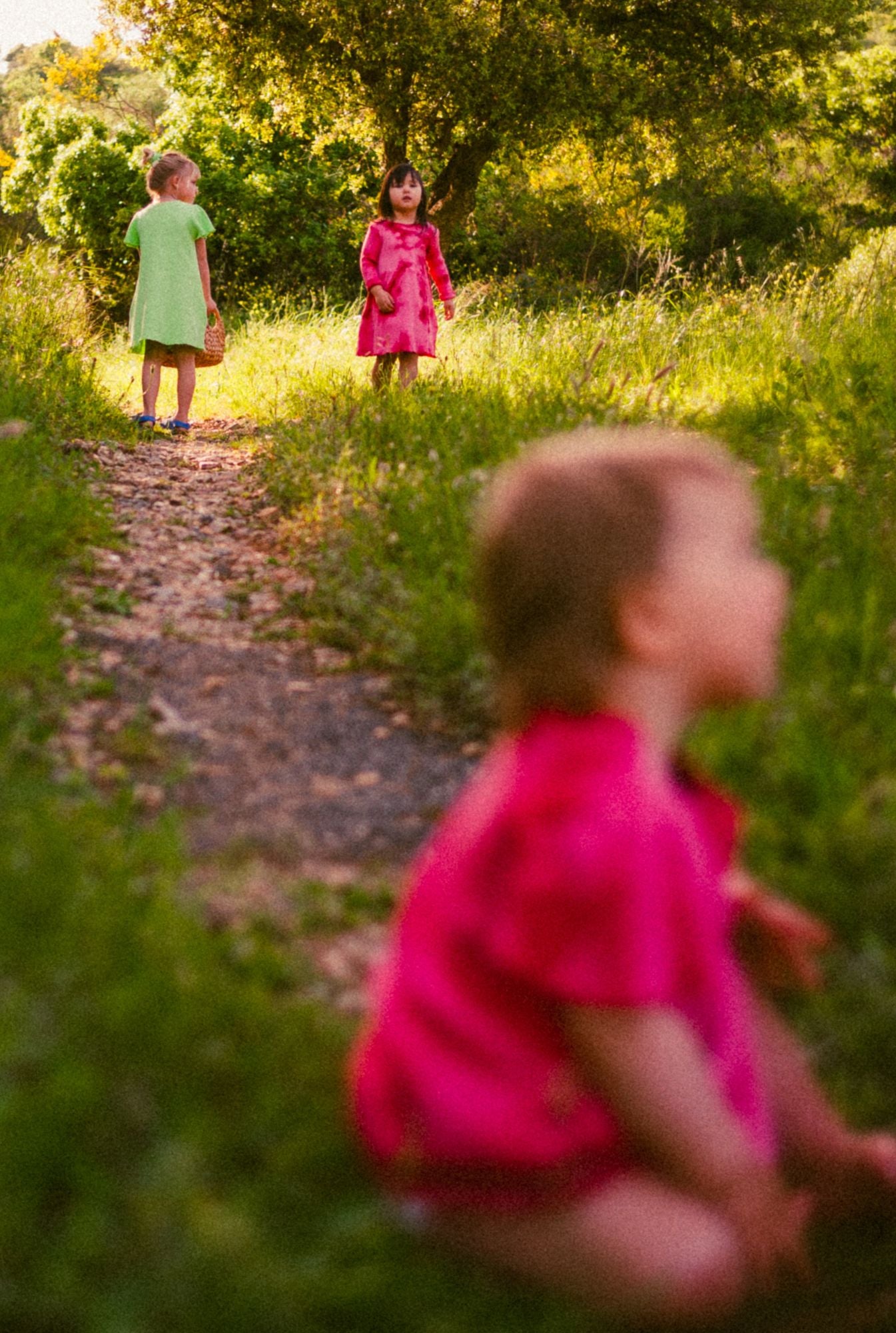 1 year old girl is playing with flowers and wearing a beautiful, comfortable, and colorful dress in pink tie dye. The dress is made by Tiny Advocates. It comes in a variety of beautiful colors, has side pockets, and beautiful details around the neckline and sleeves.