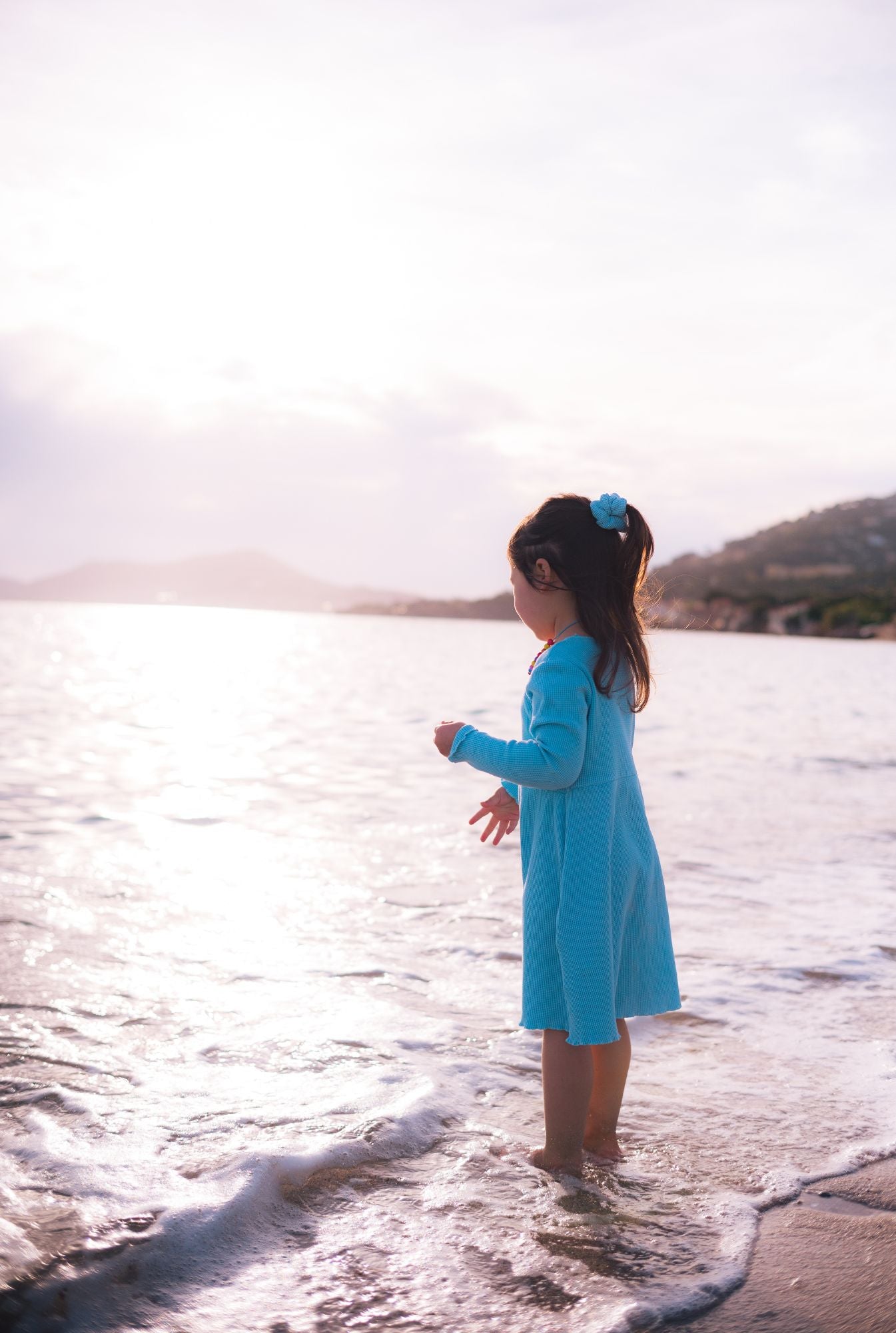 A little girl playing by the beach and wearing a long sleeve comfortable dress. It's made from 100% organic cotton dress and garment dyed in natural minerals.