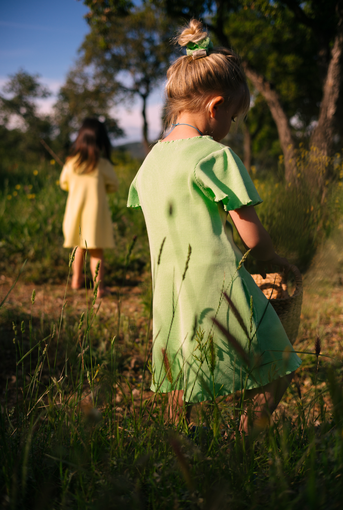 A little girl playing in the field in South of France. She is wearing a beautiful light green dress made from 100% organic cotton. The dress is soft, comfortable and comes with side pockets. 