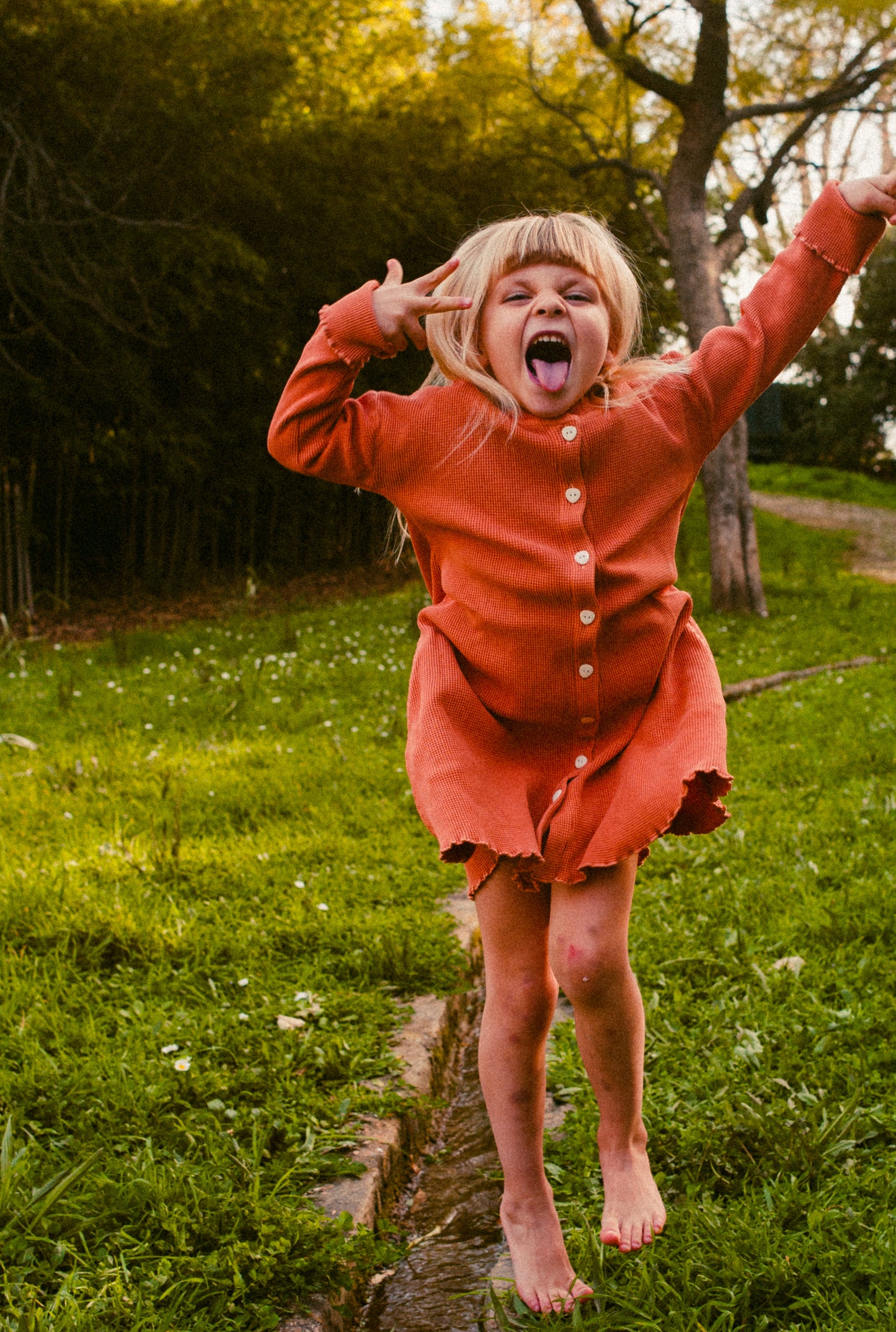 a 6 year old girl wearing a comfortable long sleeve dress with buttons and pockets. The dress is made with 100% organic cotton and garment dyed in natural minerals. It is comfortable and breathable for everyday wear.